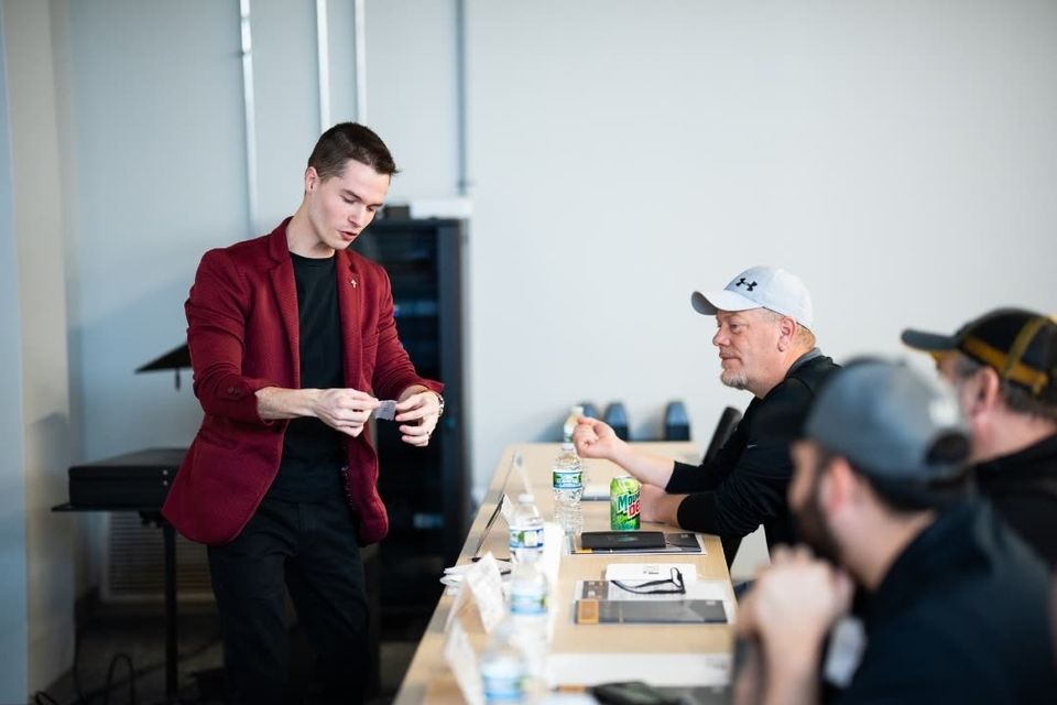 Trade show attendees gathered around Caleb Hyatt at a booth — available in Detroit